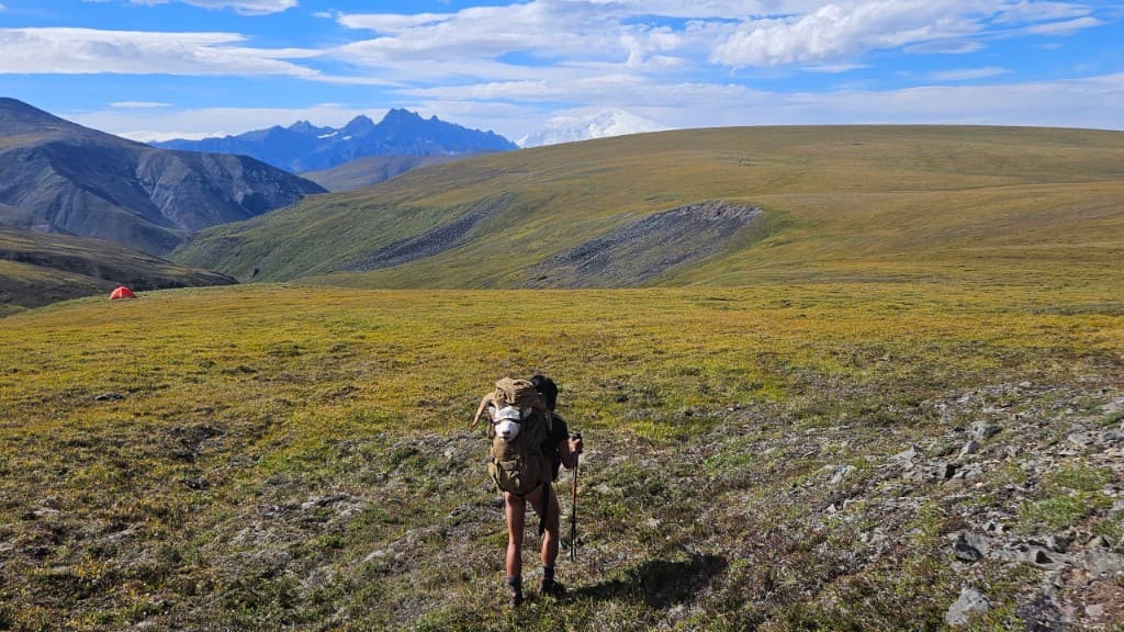 Backcountry hiking through alpine tundra toward distant mountains