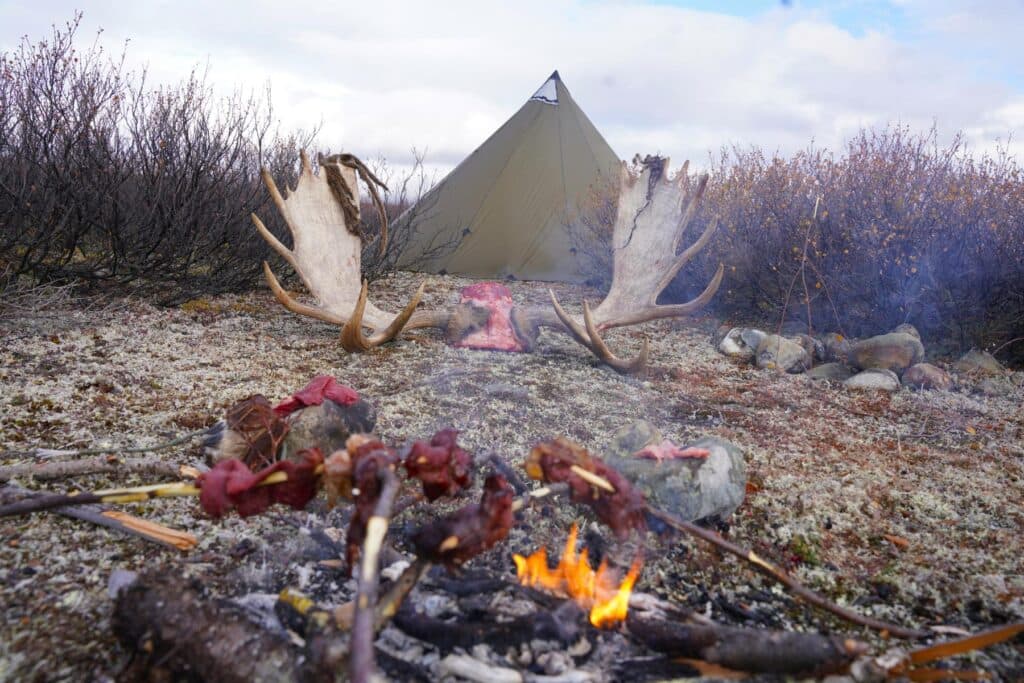 Subsistence camp — meat drying over fire with moose antlers and tipi