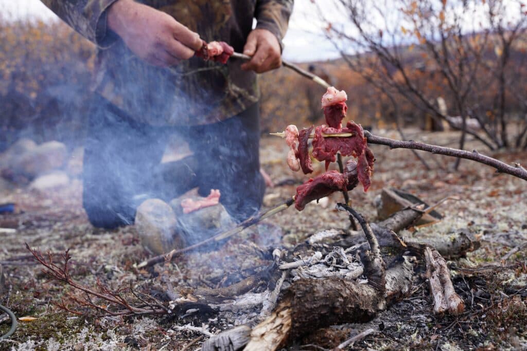 Preparing wild game meat over an open fire