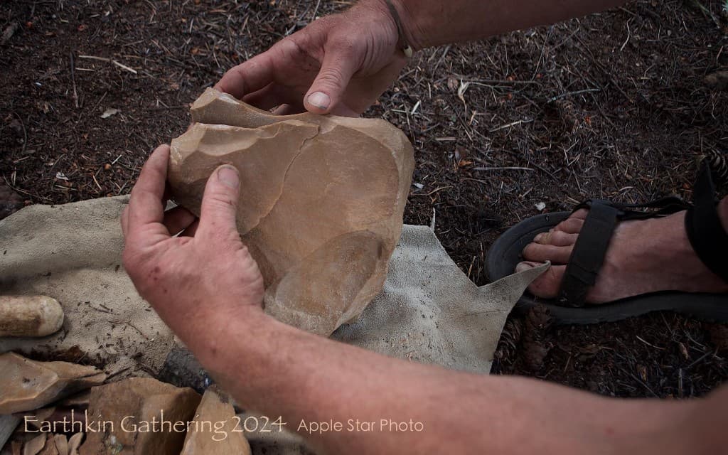 Hands shaping a stone core during flintknapping at Earthkin Gathering