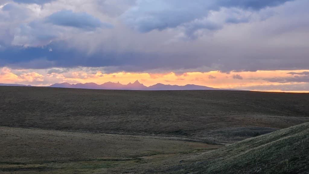 Sunset over distant mountain spires on the open tundra